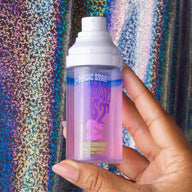 Hand holding a bottle of 'Magic Star' product against a colorful, textured background