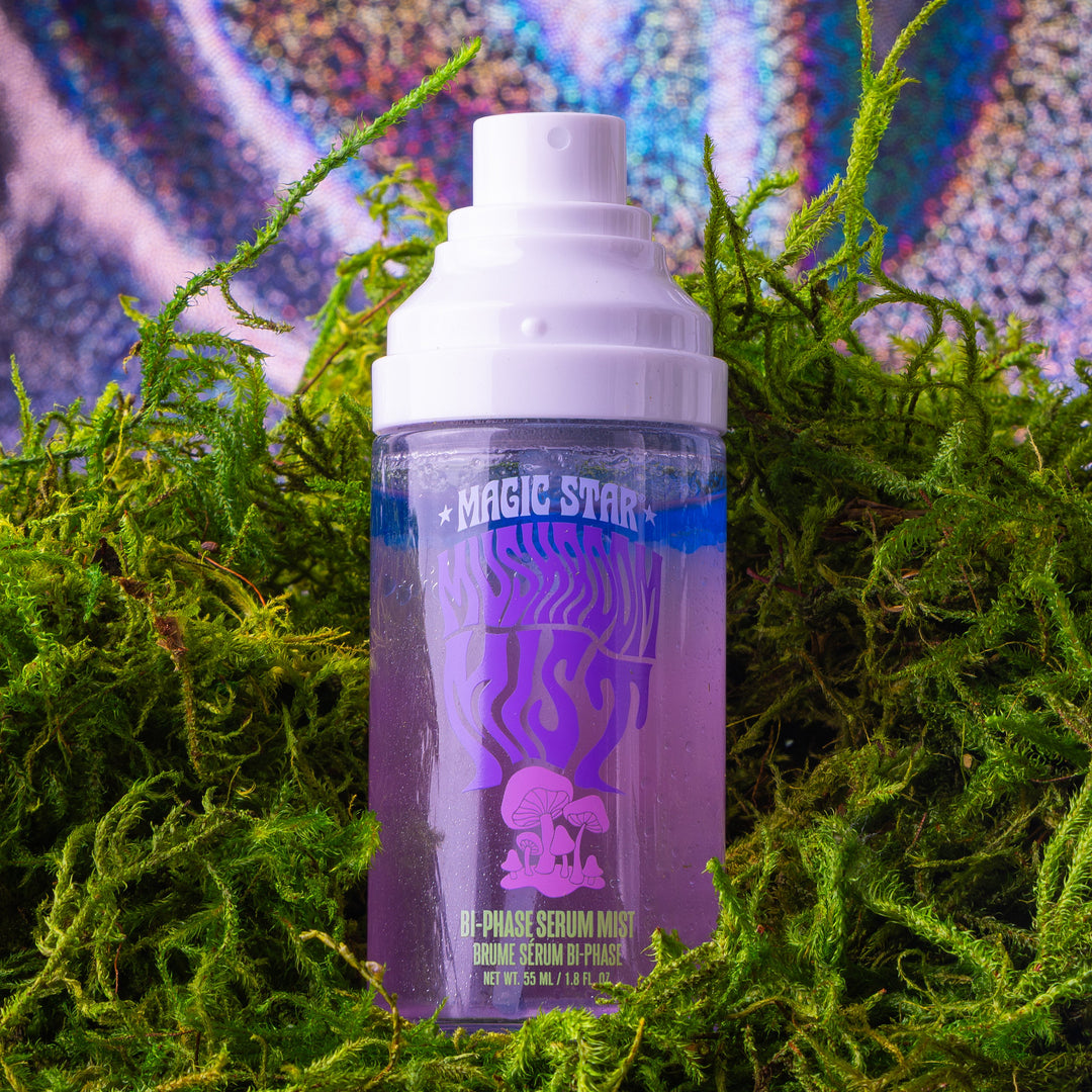 Purple spray bottle with white cap on green foliage against a colorful abstract background